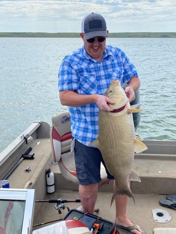 A man is holding a large fish on a boat.