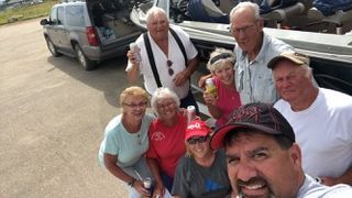 A group of people are posing for a picture in front of a boat.