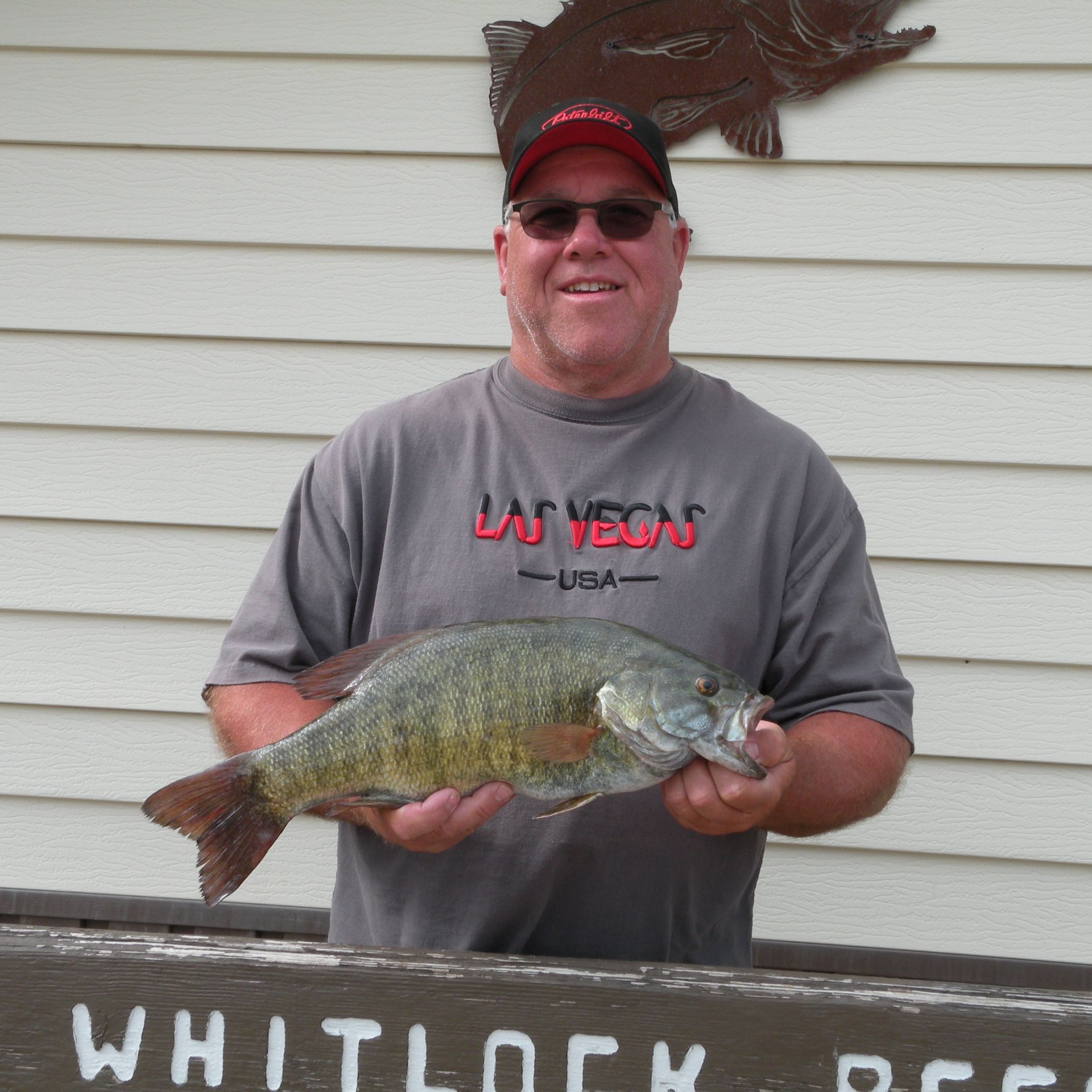 A man in a las vegas shirt is holding a large fish
