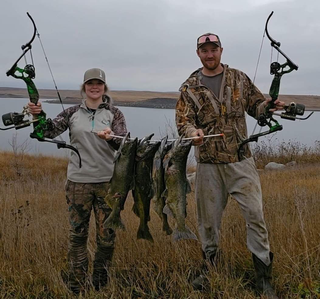 A man and a woman holding bows and arrows in a field