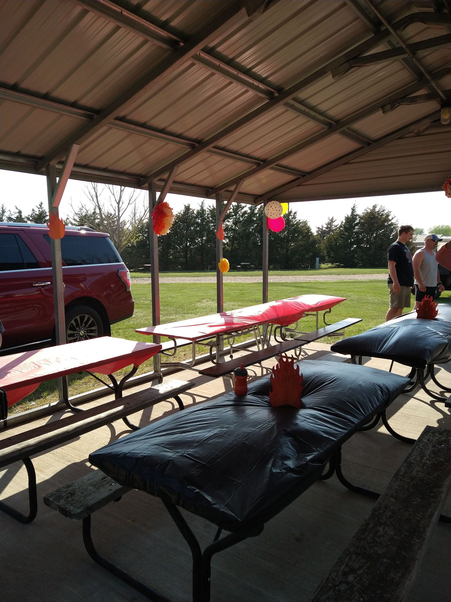 A group of picnic tables under a canopy with balloons on them