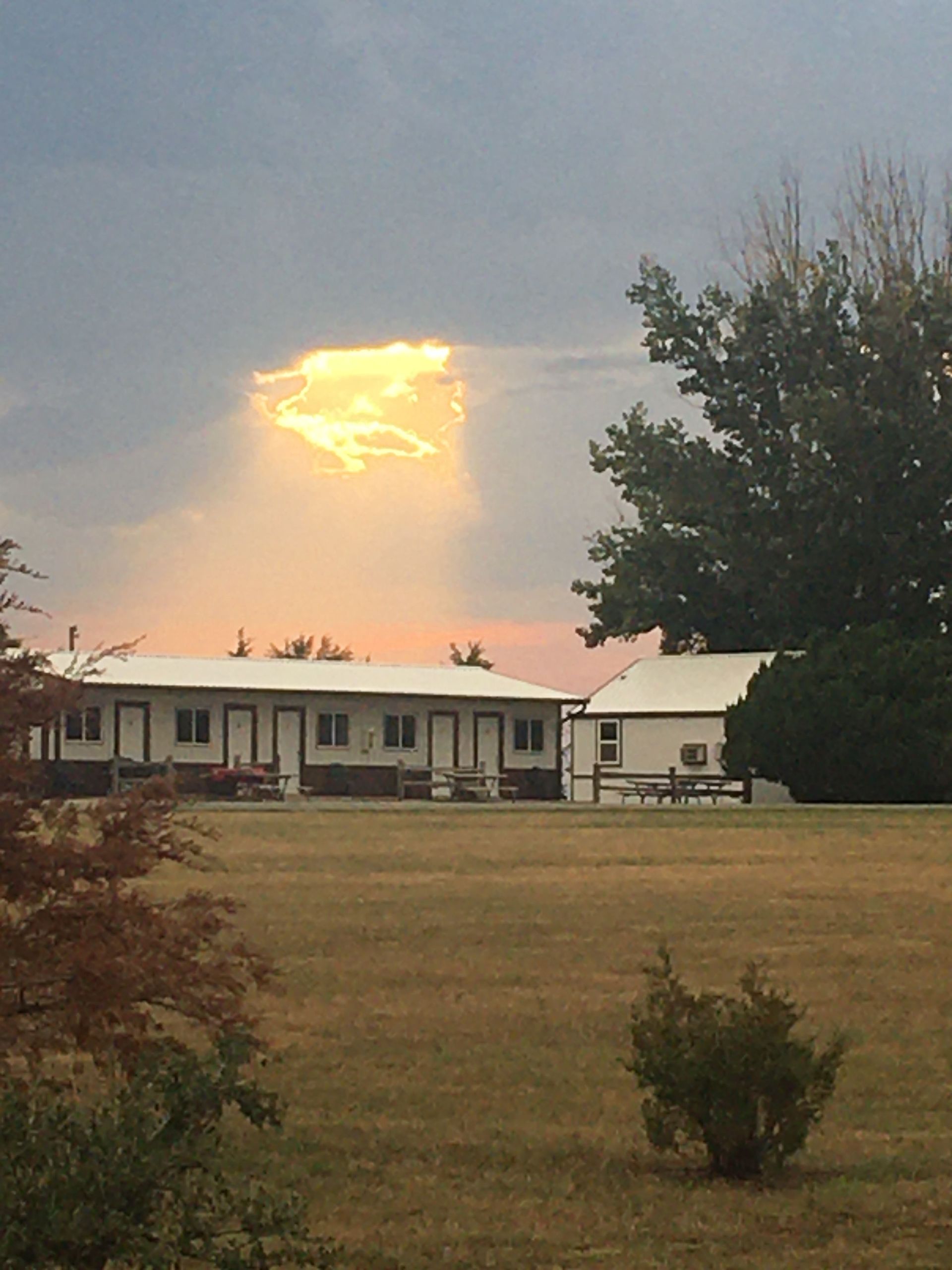 A house in a field with a sunset in the background