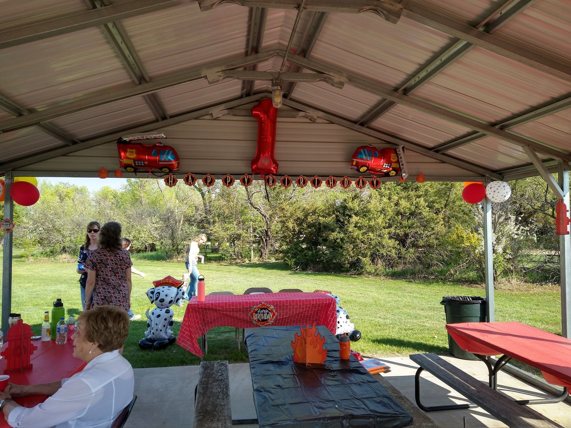 A woman is sitting at a picnic table under a covered pavilion.