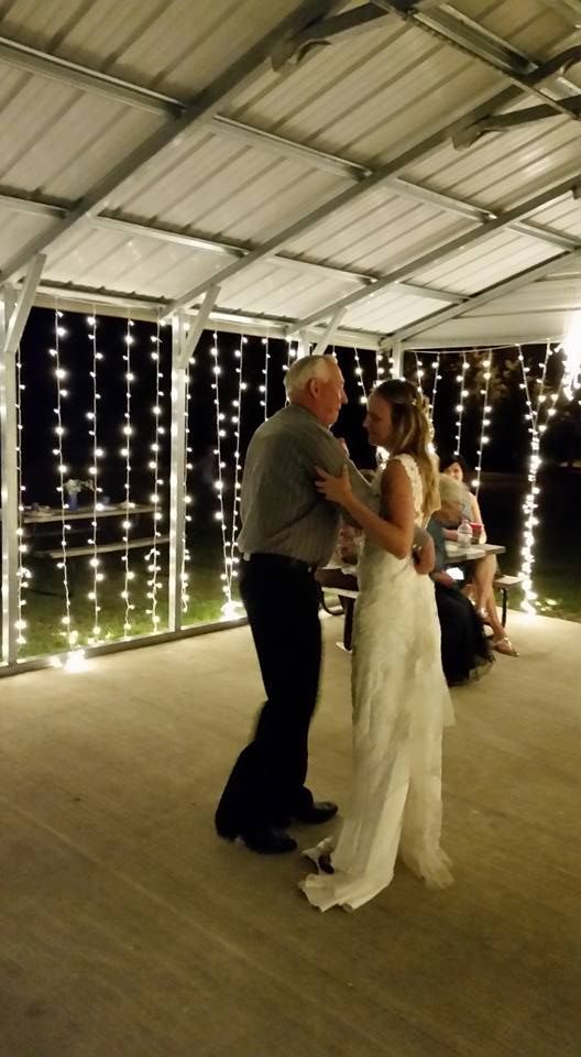 A bride and groom are dancing under a canopy at a wedding reception.