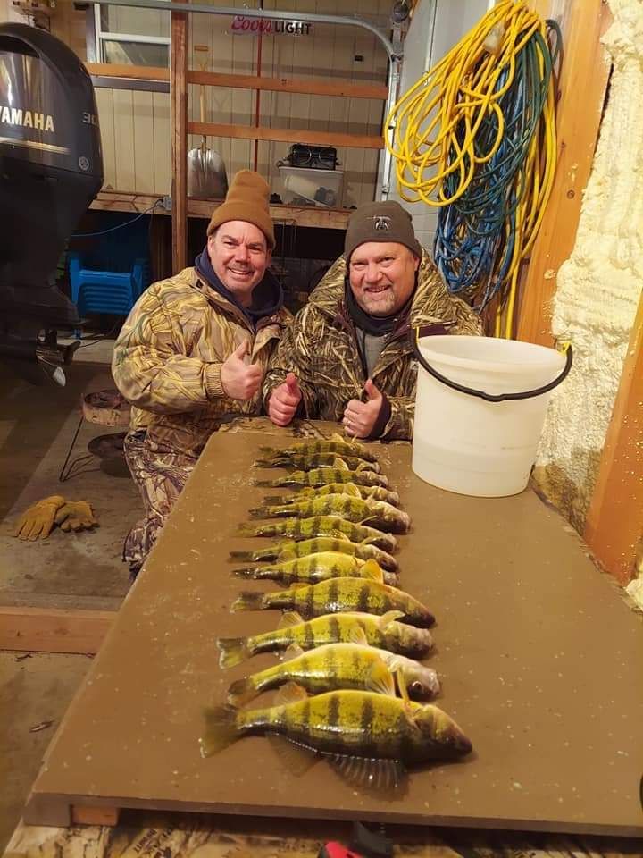 Two men are sitting at a table with a bunch of fish on it.