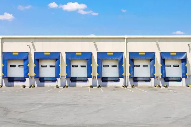 Loading docks on a warehouse building with blue and yellow accents against a blue sky.