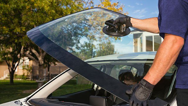 A man is installing a windshield on a car.