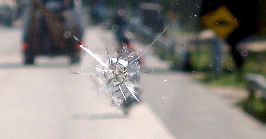 A close up of a broken windshield on a road.