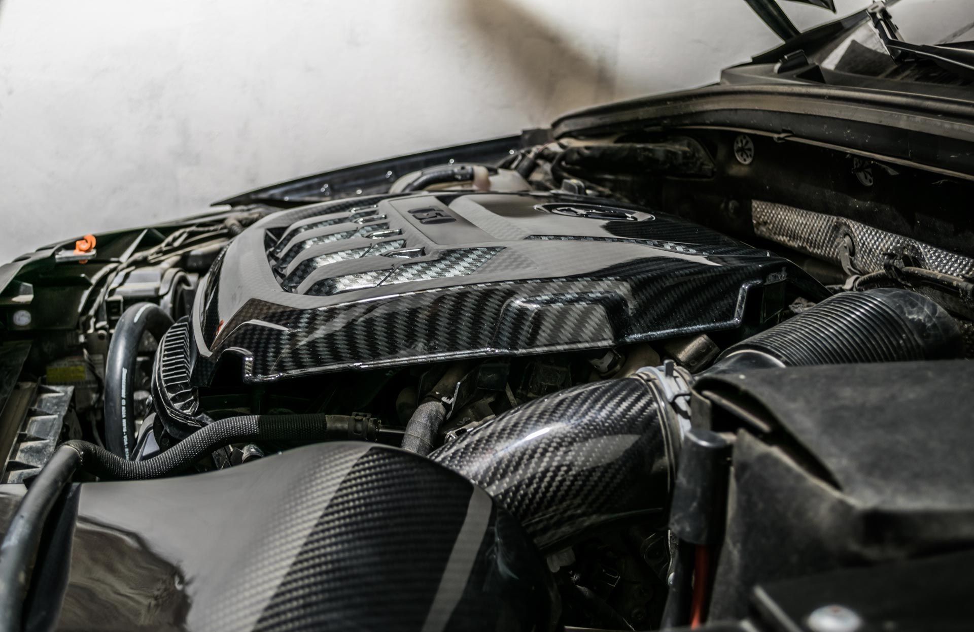 Close-up of a carbon-fiber car engine bay with hoses and components under the hood