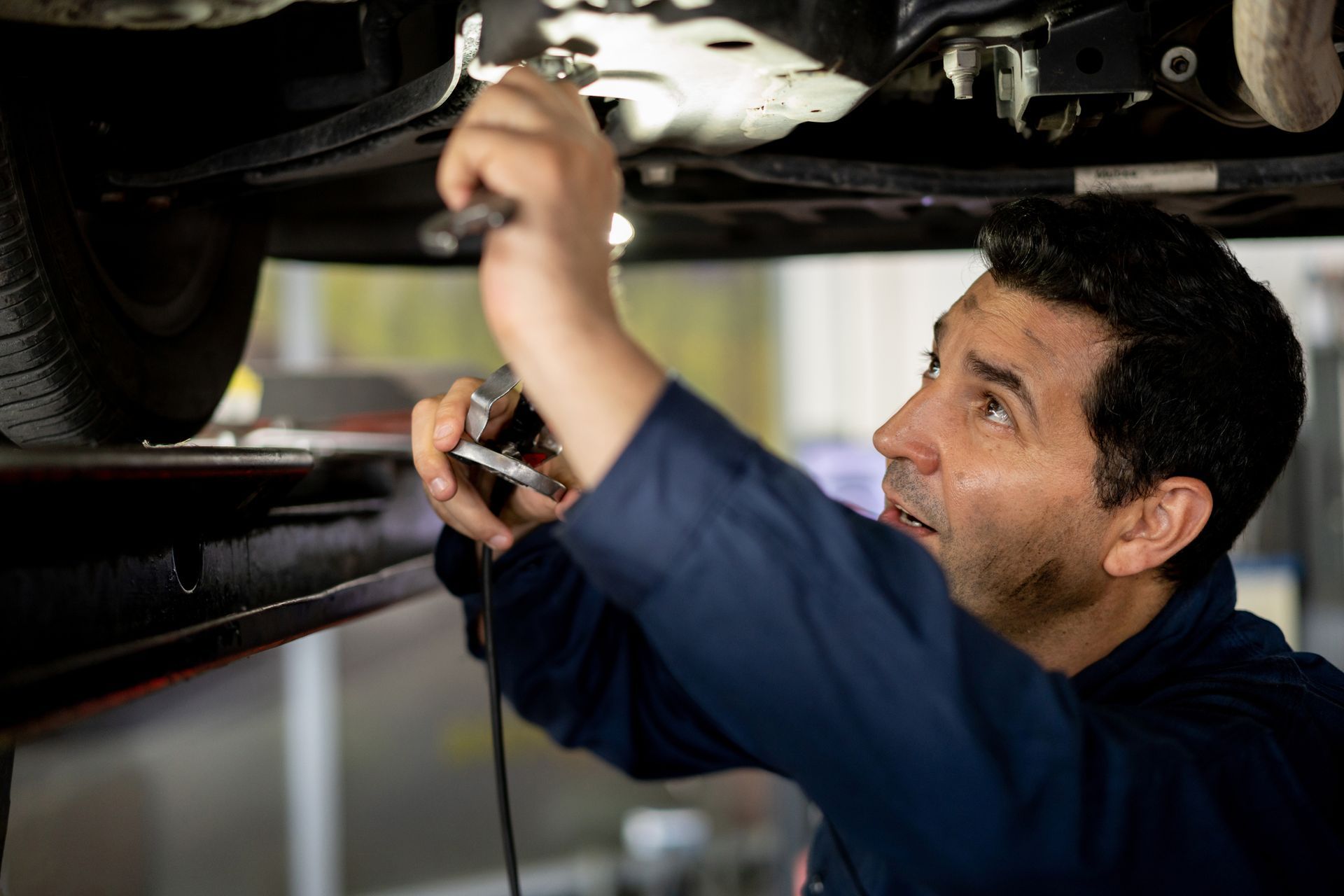 Male mechanic working under a car providing expert Jaguar Maintenance services.