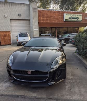 A black jaguar f type is parked in front of a building.