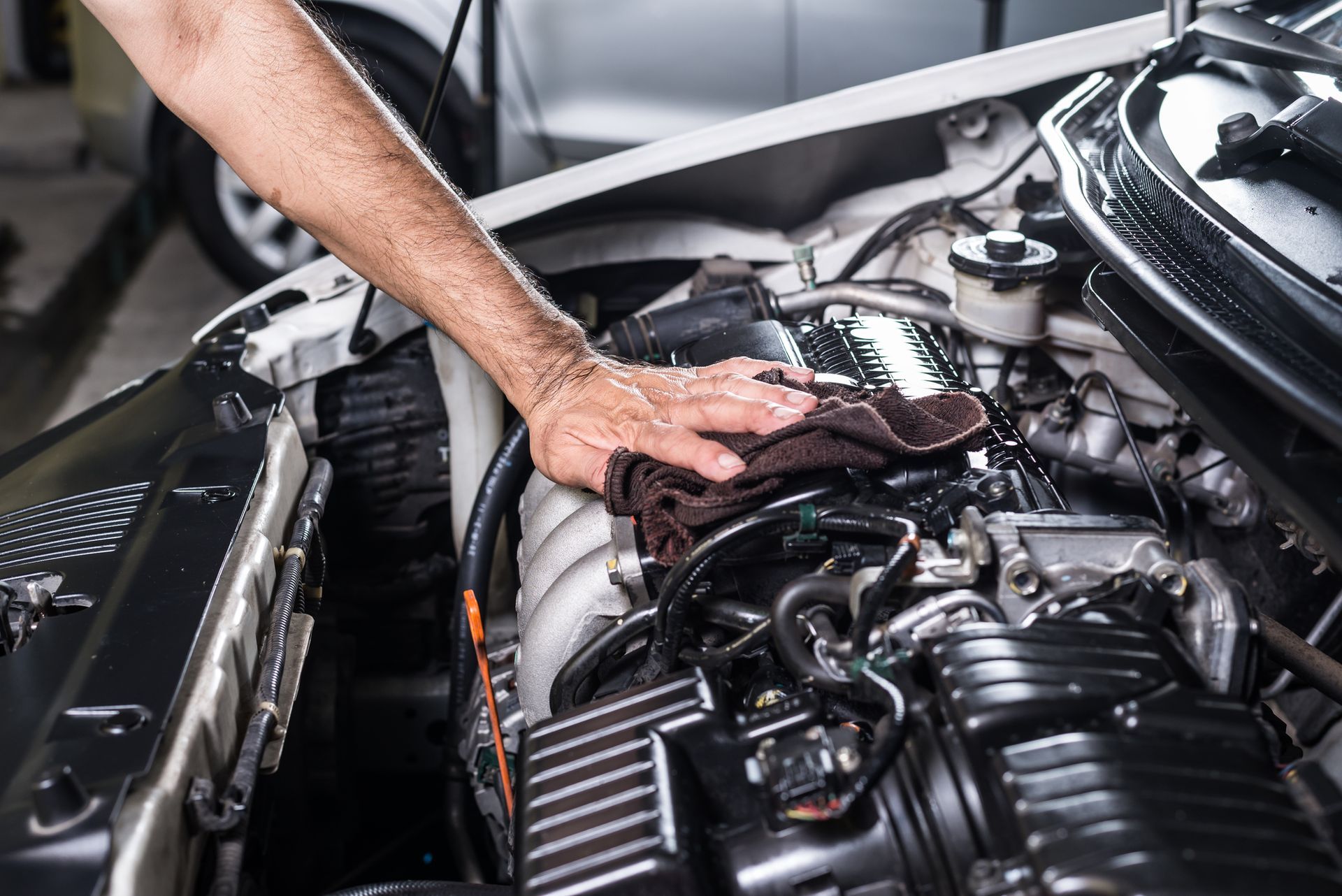 A mechanic's hand inspecting a vehicle engine – Land Rover Repair Experts La Jolla