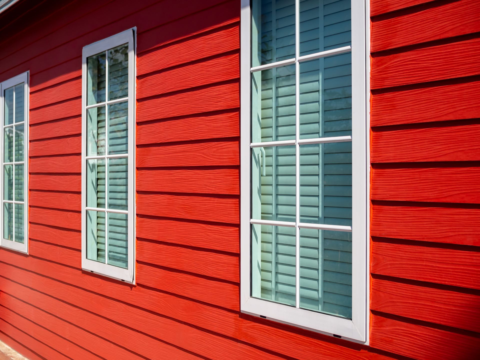 Bright red wooden wall with white-framed windows.