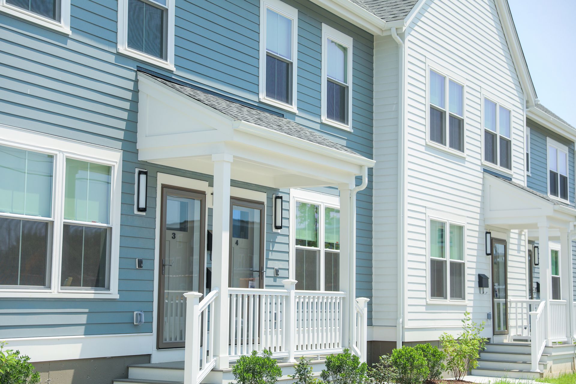 Row of blue and white townhouses with small front porches and windows.