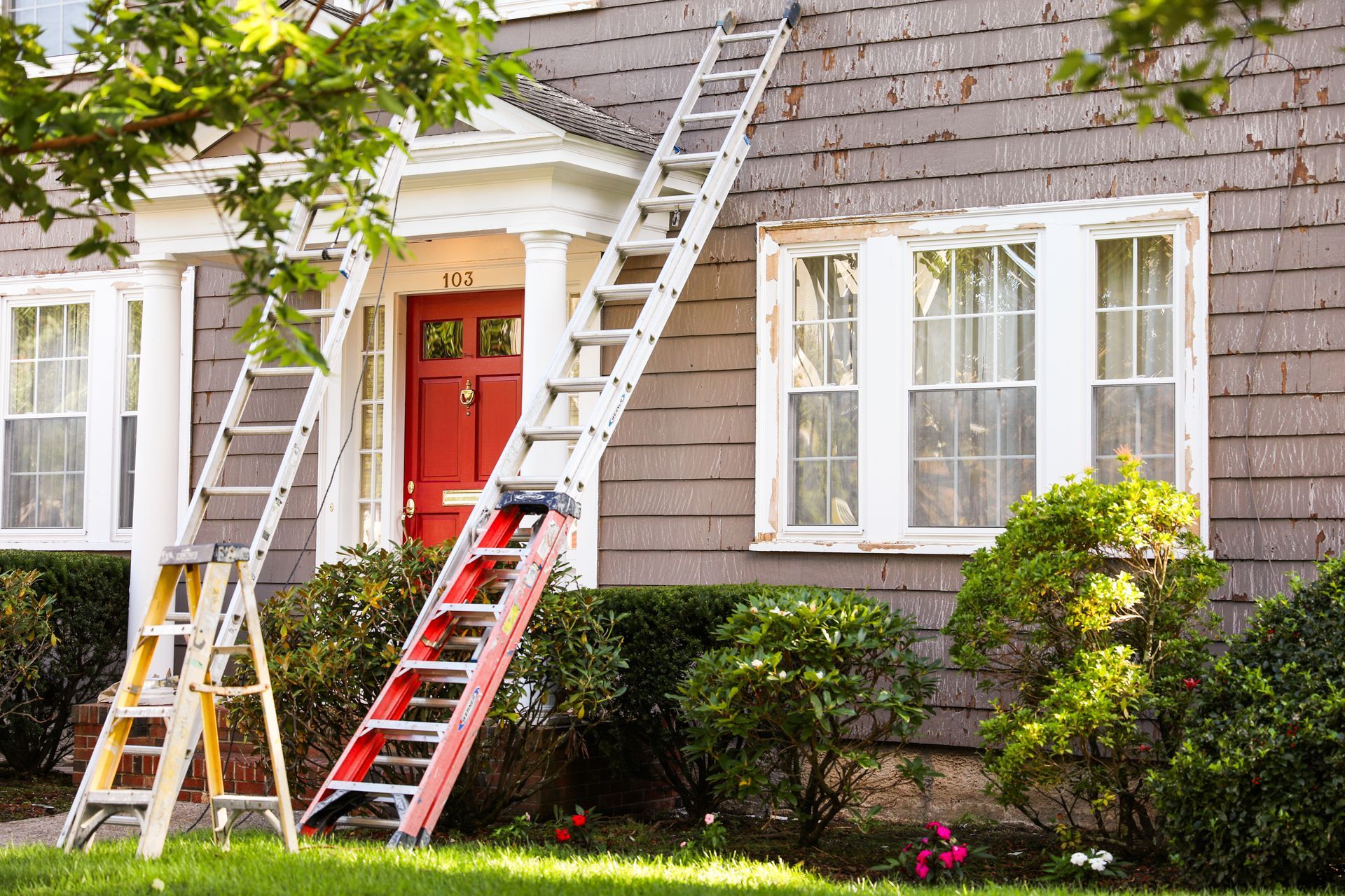 Ladders against house with red door.