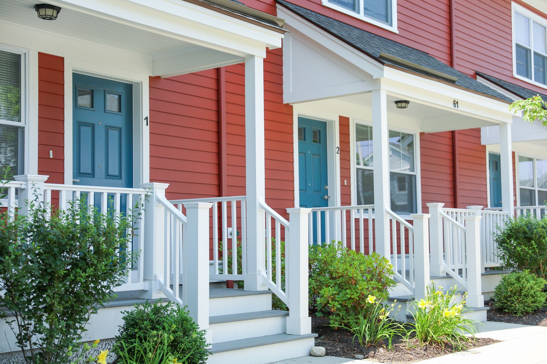 Red townhouses with white porches and teal doors.
