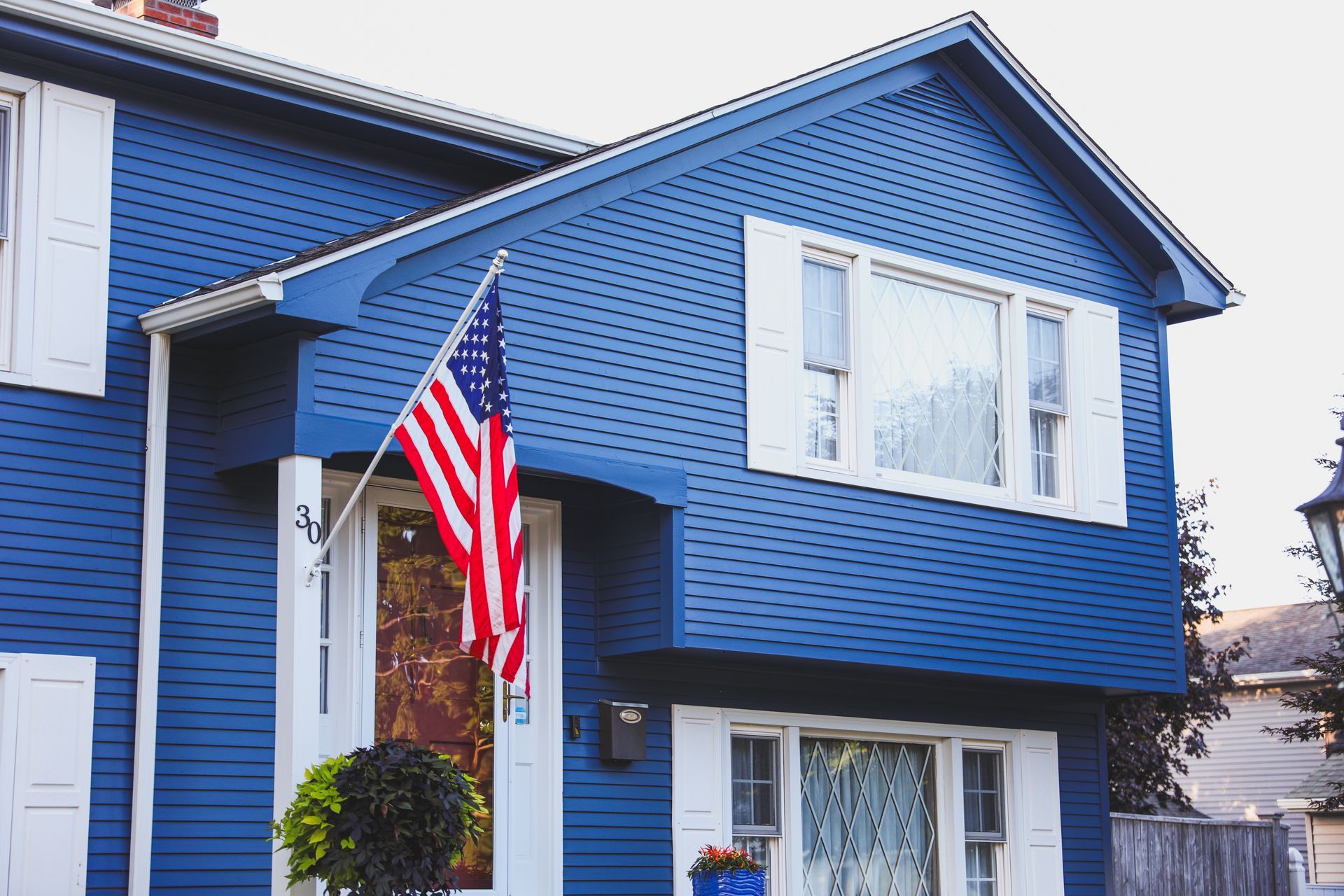 Blue house with white trim and an American flag.