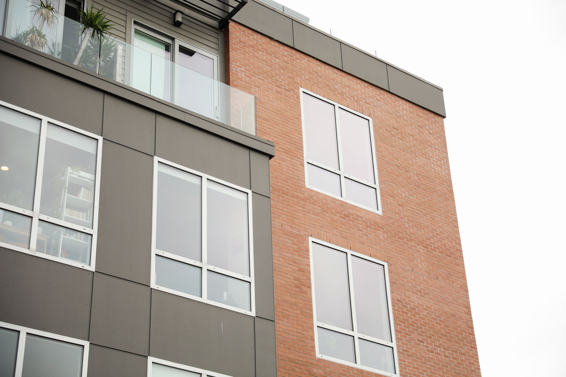 Modern buildings with brick facade and dark grey siding, windows, and balcony.
