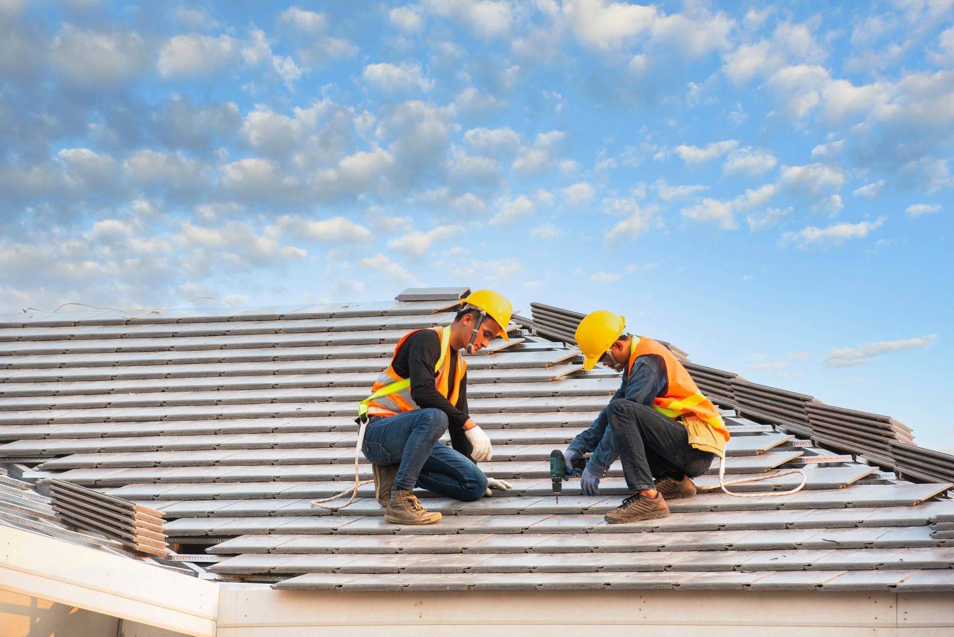 two construction workers are working on the roof of a house .