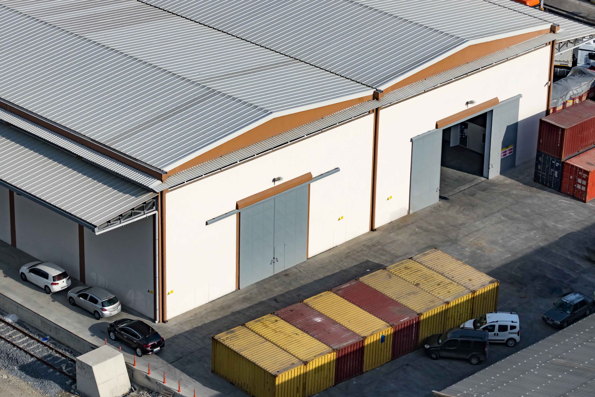 an aerial view of a warehouse filled with containers and cars parked in front of it .