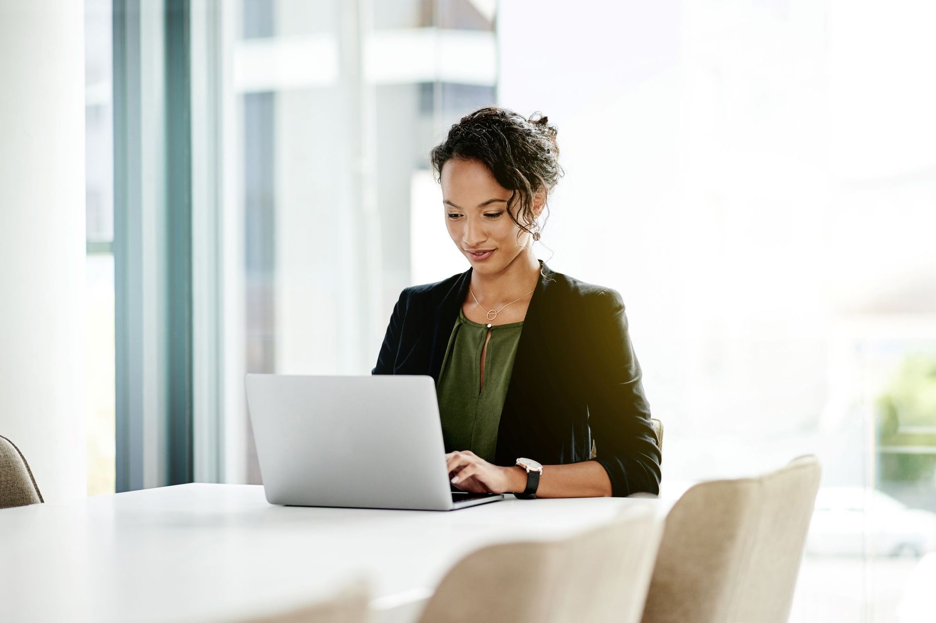 A woman is sitting at a table using a laptop computer.