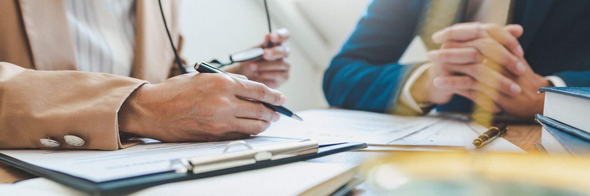 A man and a woman are sitting at a table looking at a clipboard.