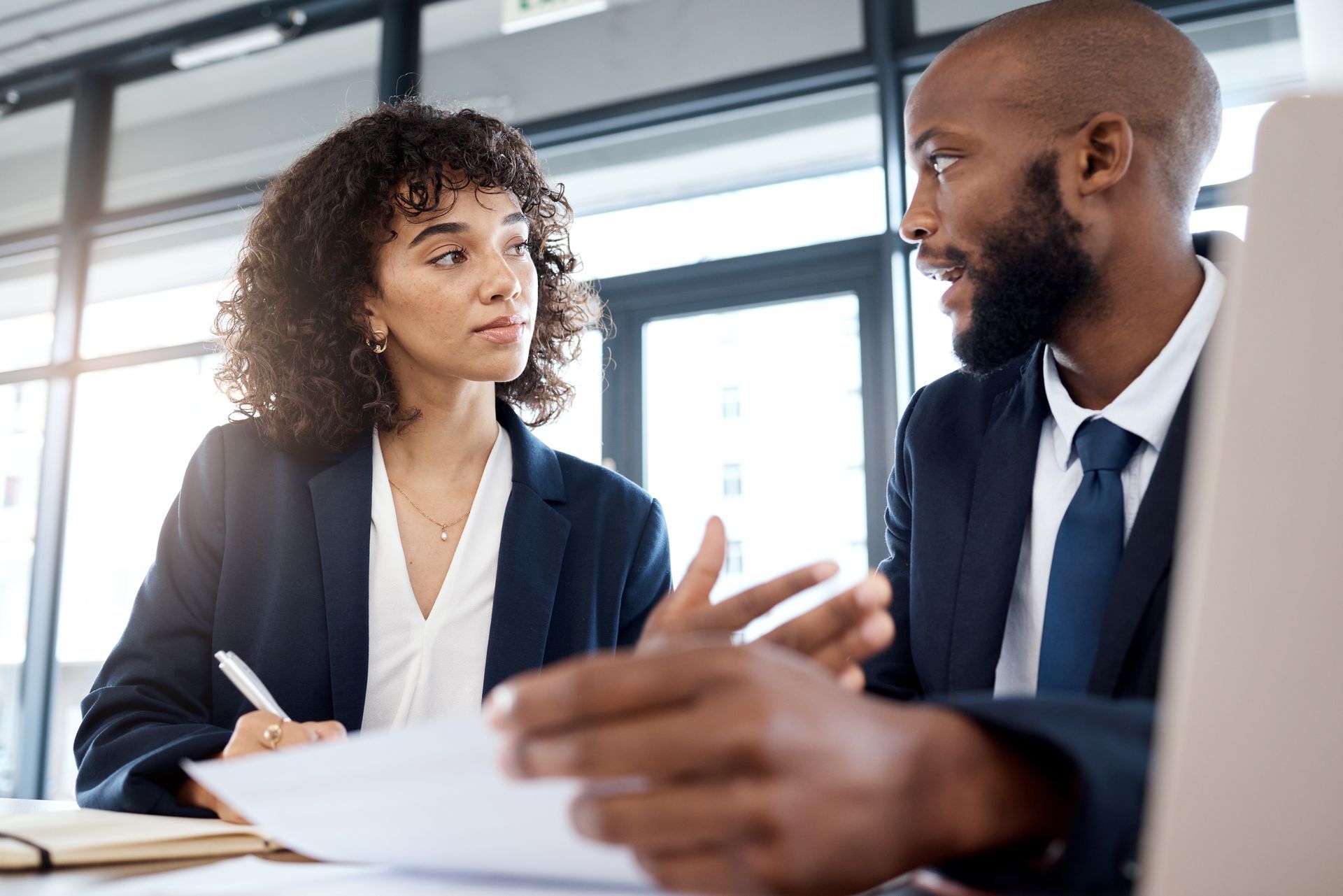 A man and a woman are sitting at a table looking at a piece of paper.