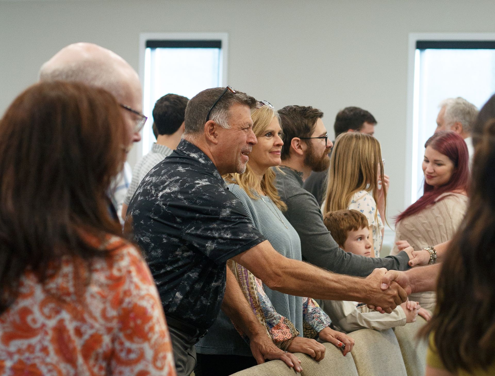 Two men are standing next to each other in a hallway holding books.