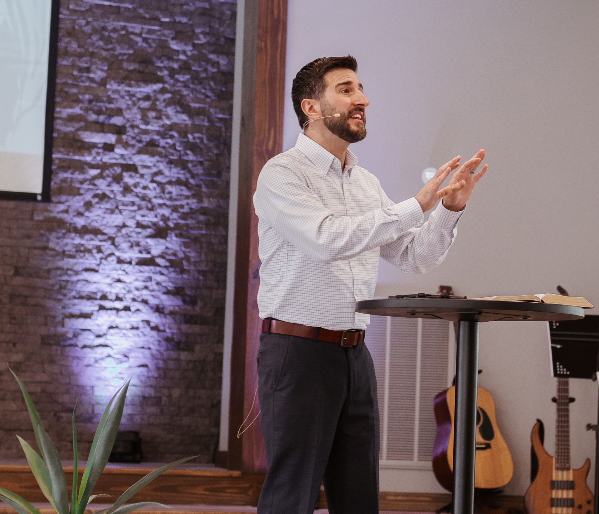 A man is standing at a podium giving a speech in front of a projector screen.