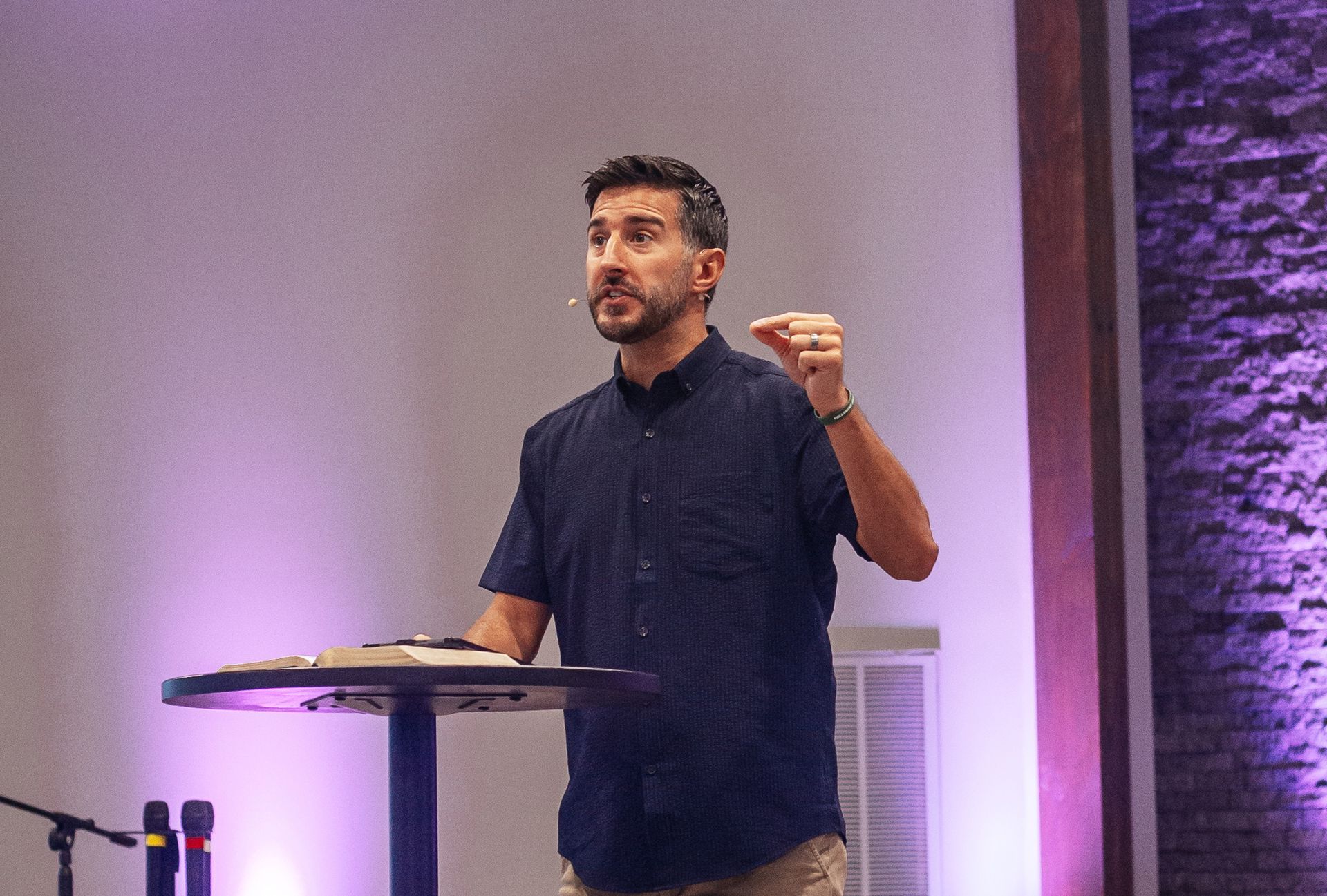 A man is standing at a podium giving a speech in front of a projector screen.