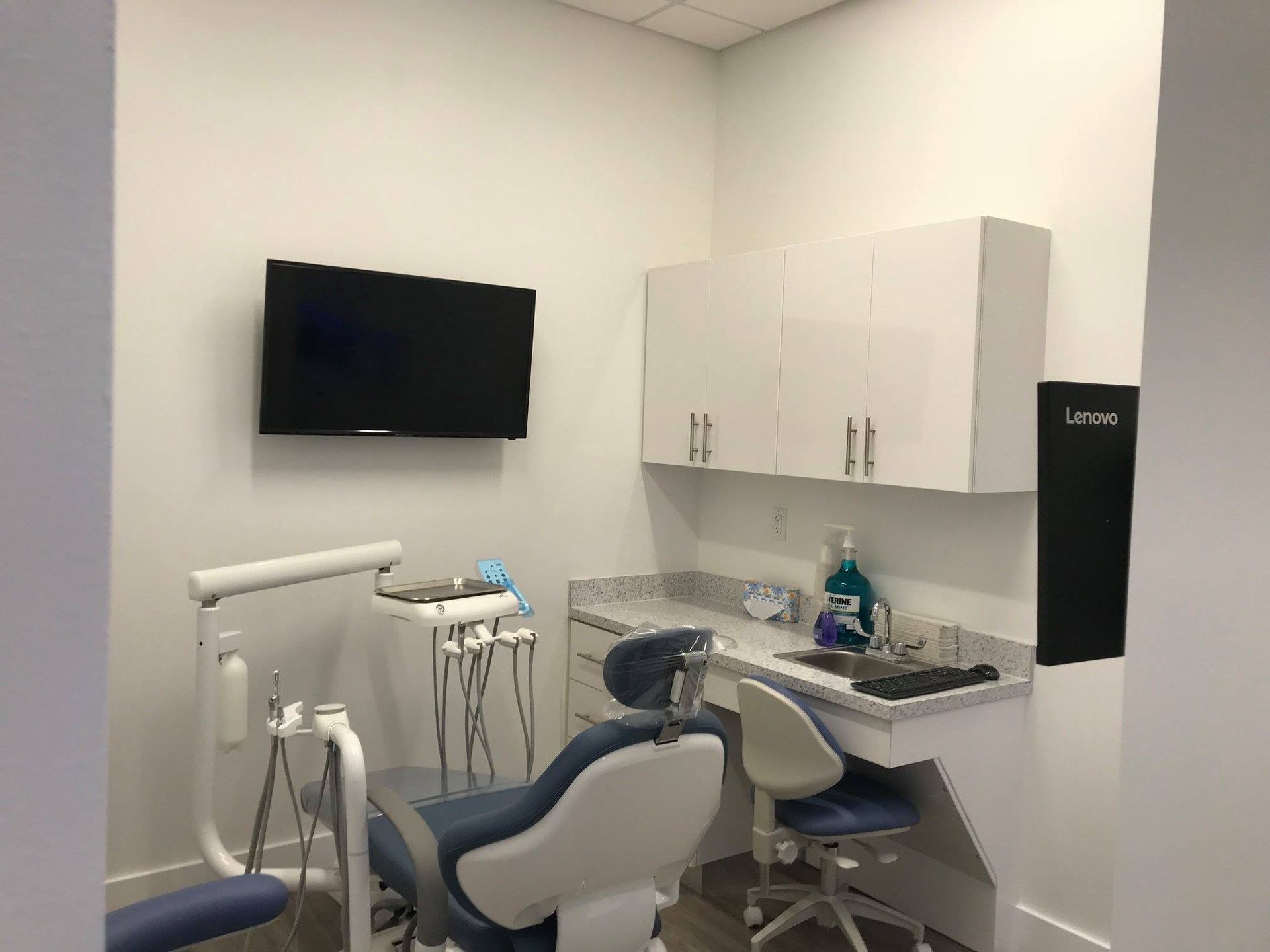 A dental office with a dental chair and a television on the wall.