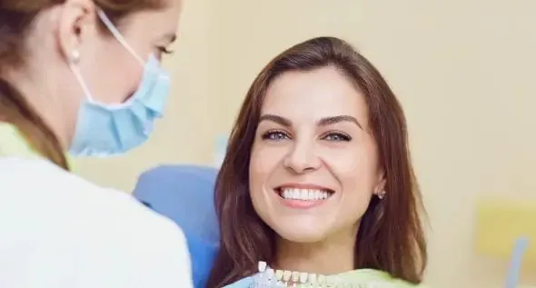 A woman is smiling while sitting in a dental chair.