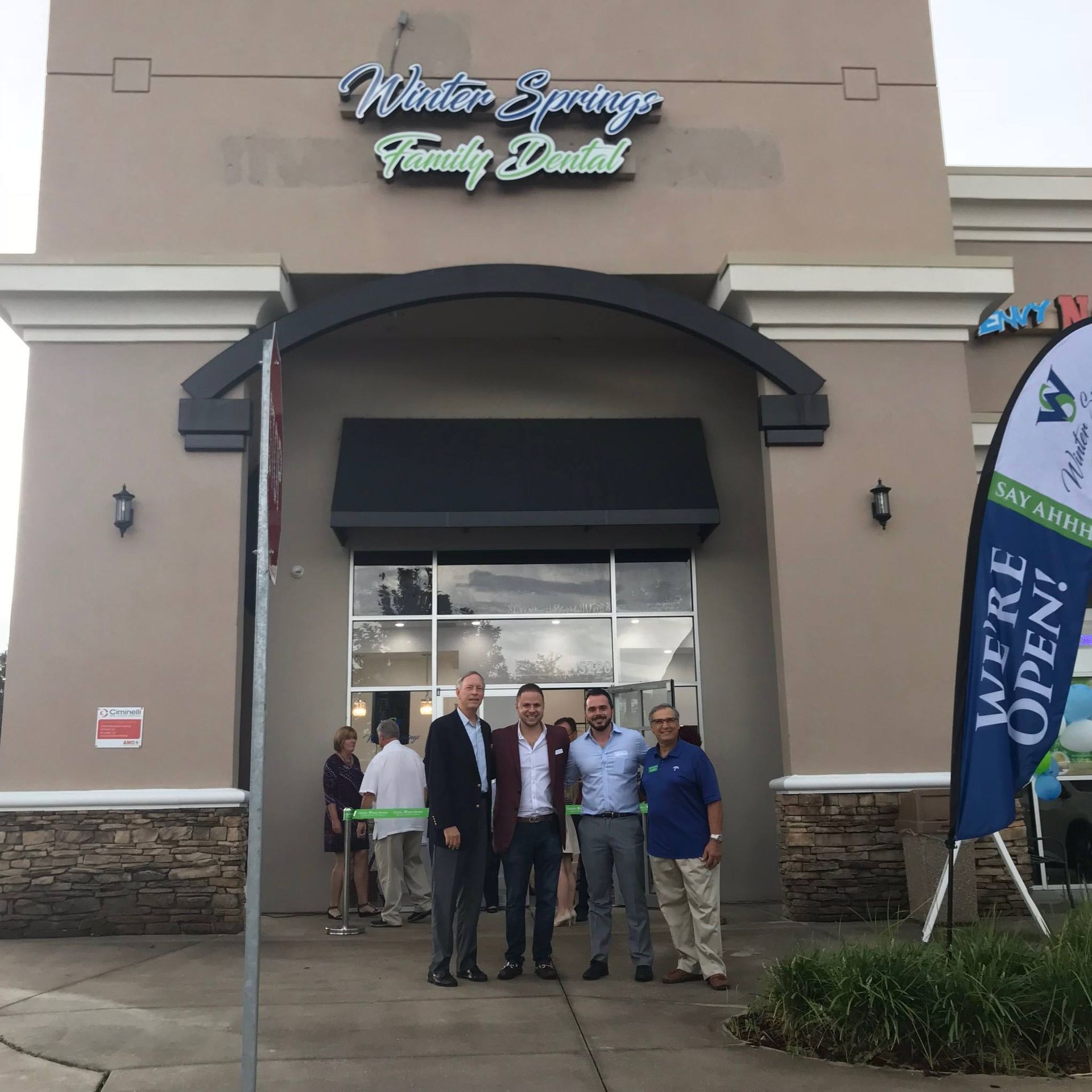 A group of men standing in front of a building that says winter springs family dental