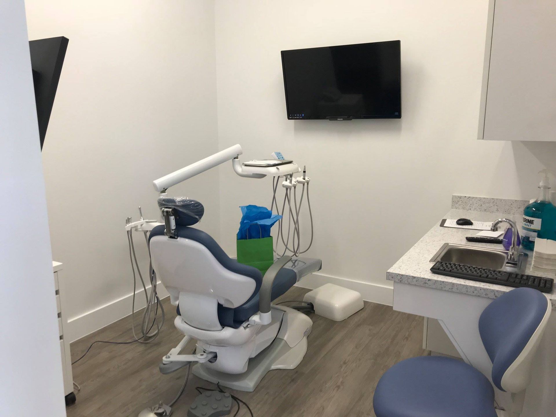 A dental office with a dental chair and a television on the wall.