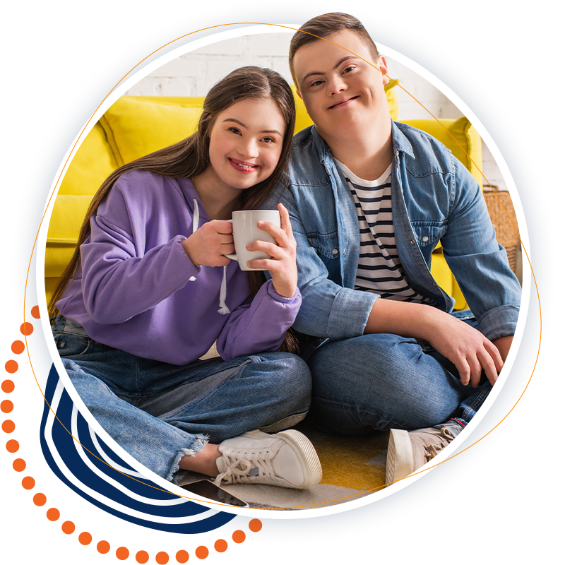 A man and a woman are sitting on the floor holding cups of coffee.