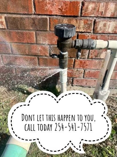 A sprinkler is spraying water on a brick wall.