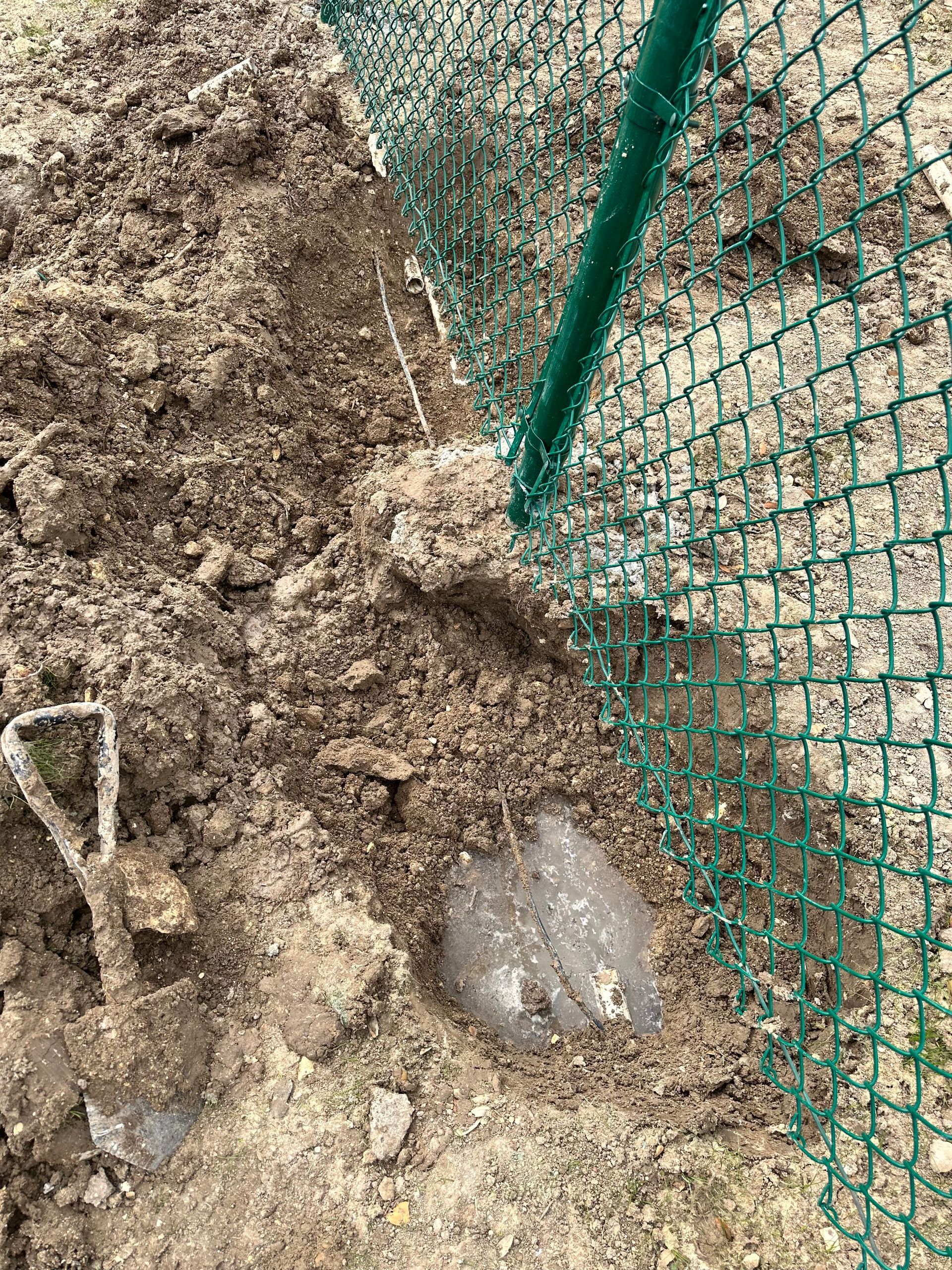 A green chain link fence is surrounding a pile of dirt.