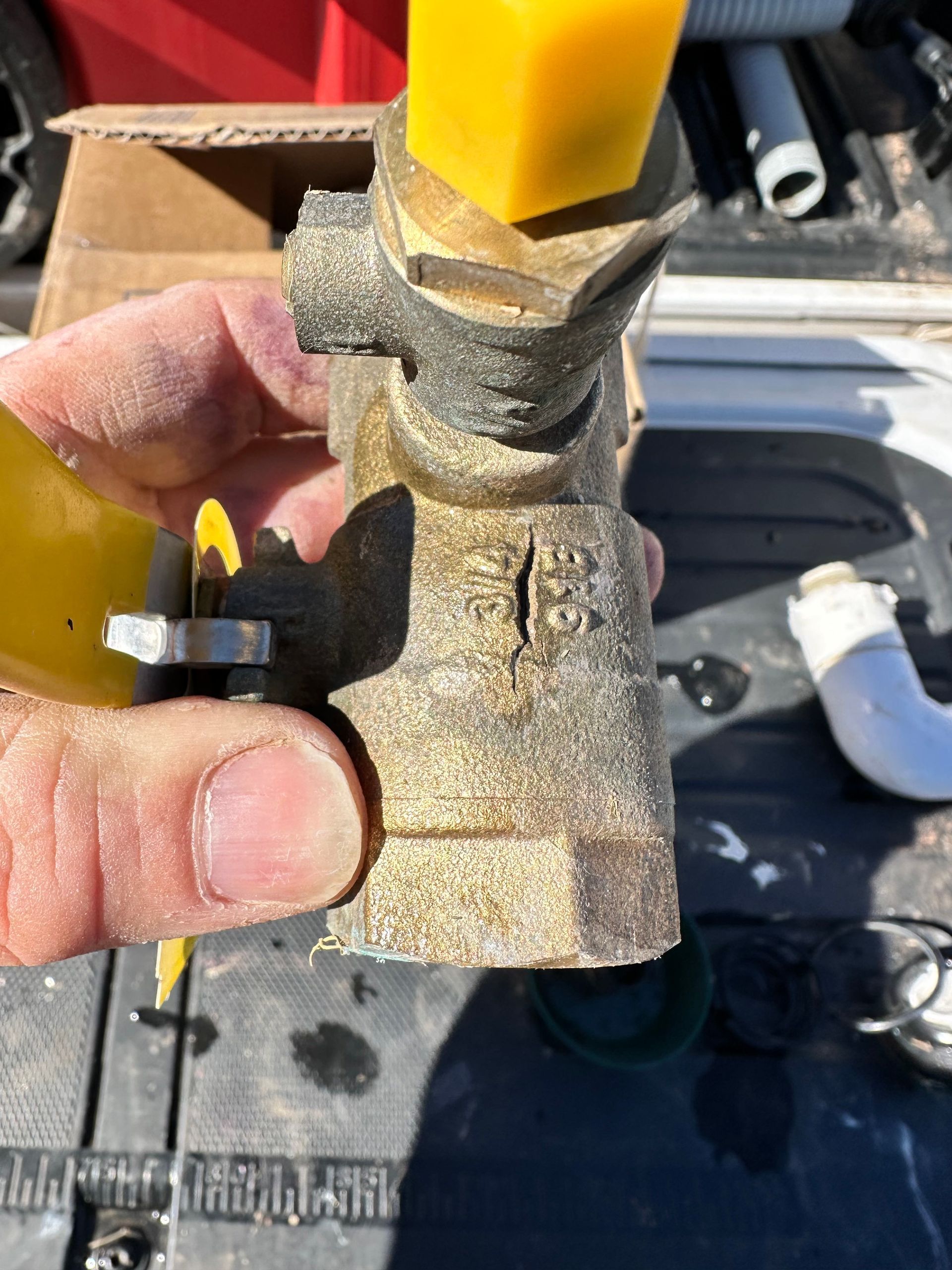 A person is holding a brass valve with a yellow cap.