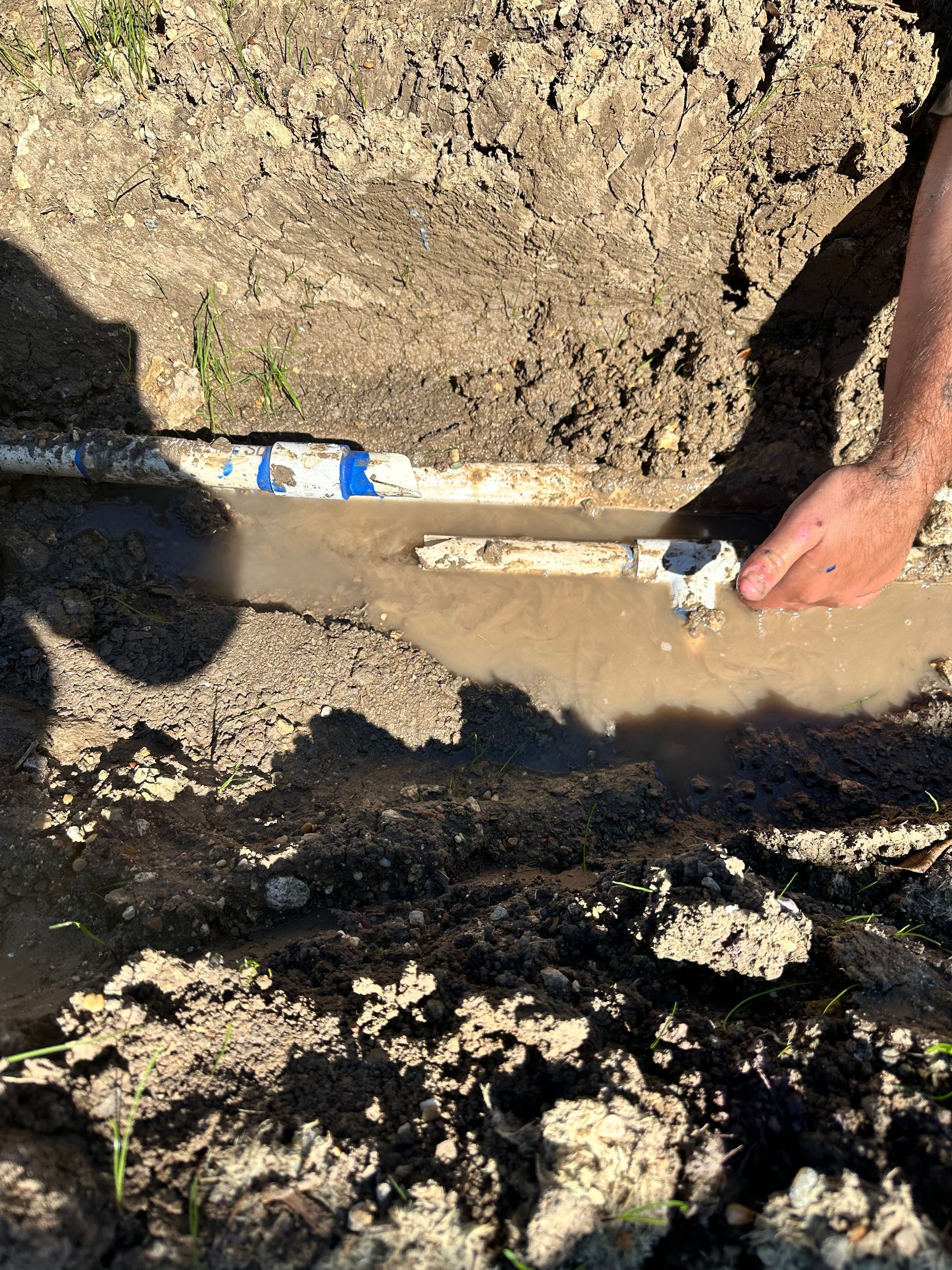A person is holding a shovel in a muddy field.