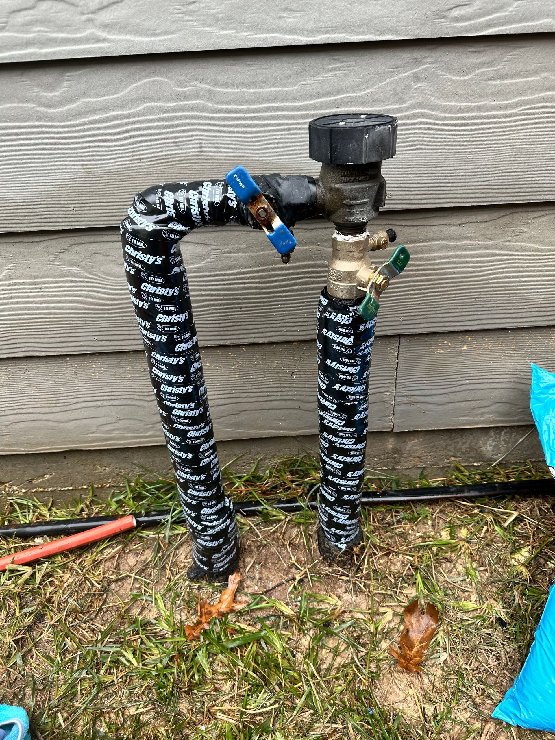 A hose is sitting in the grass next to a house.