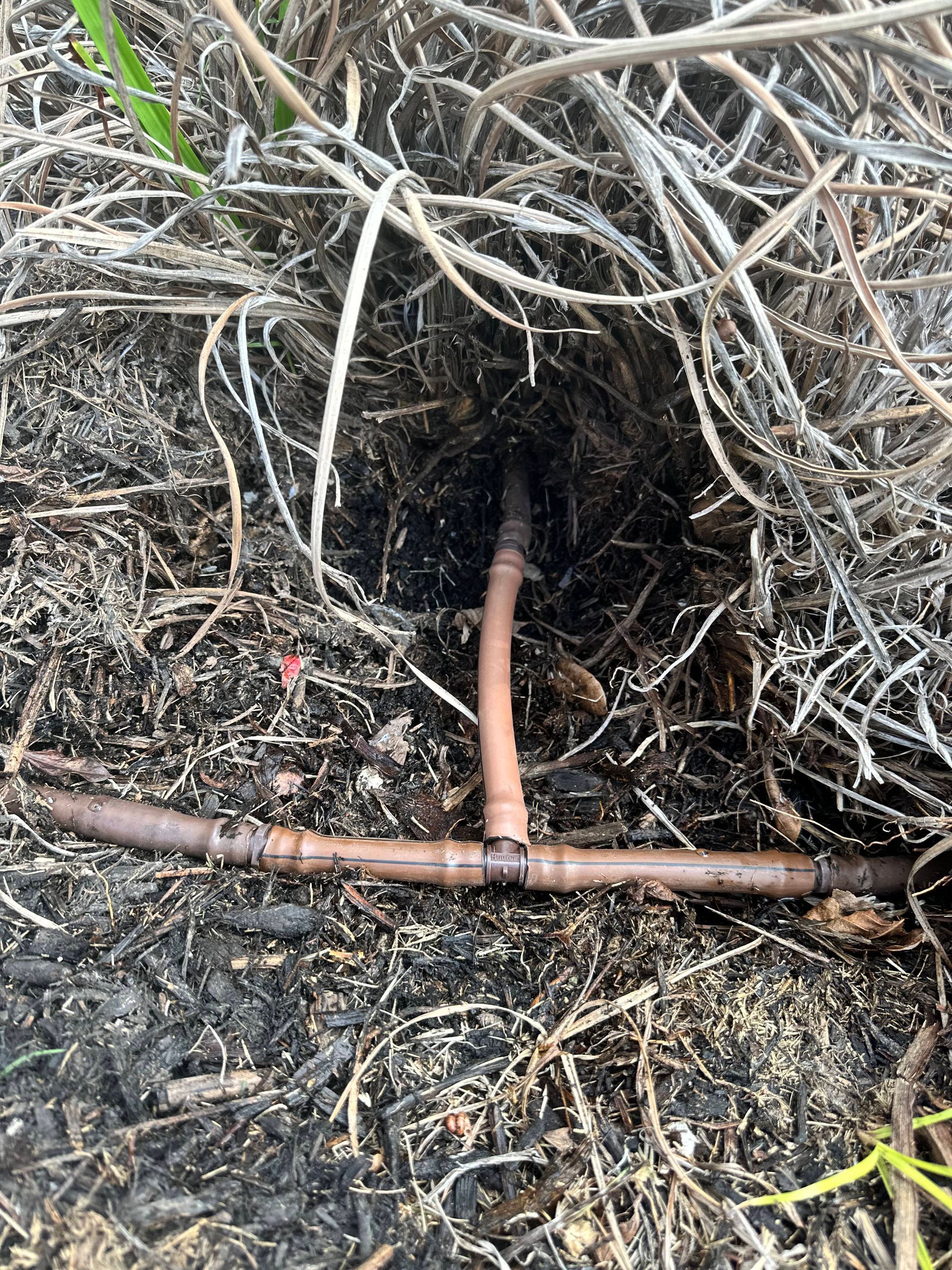 A copper pipe is laying in the dirt.
