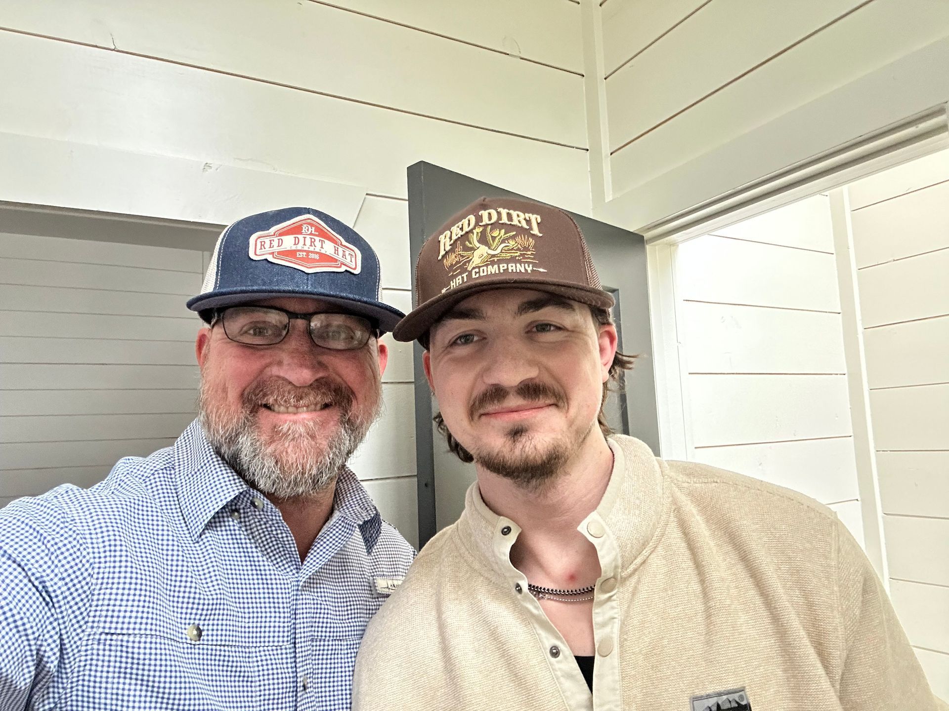 Two men wearing hats and glasses are posing for a picture.