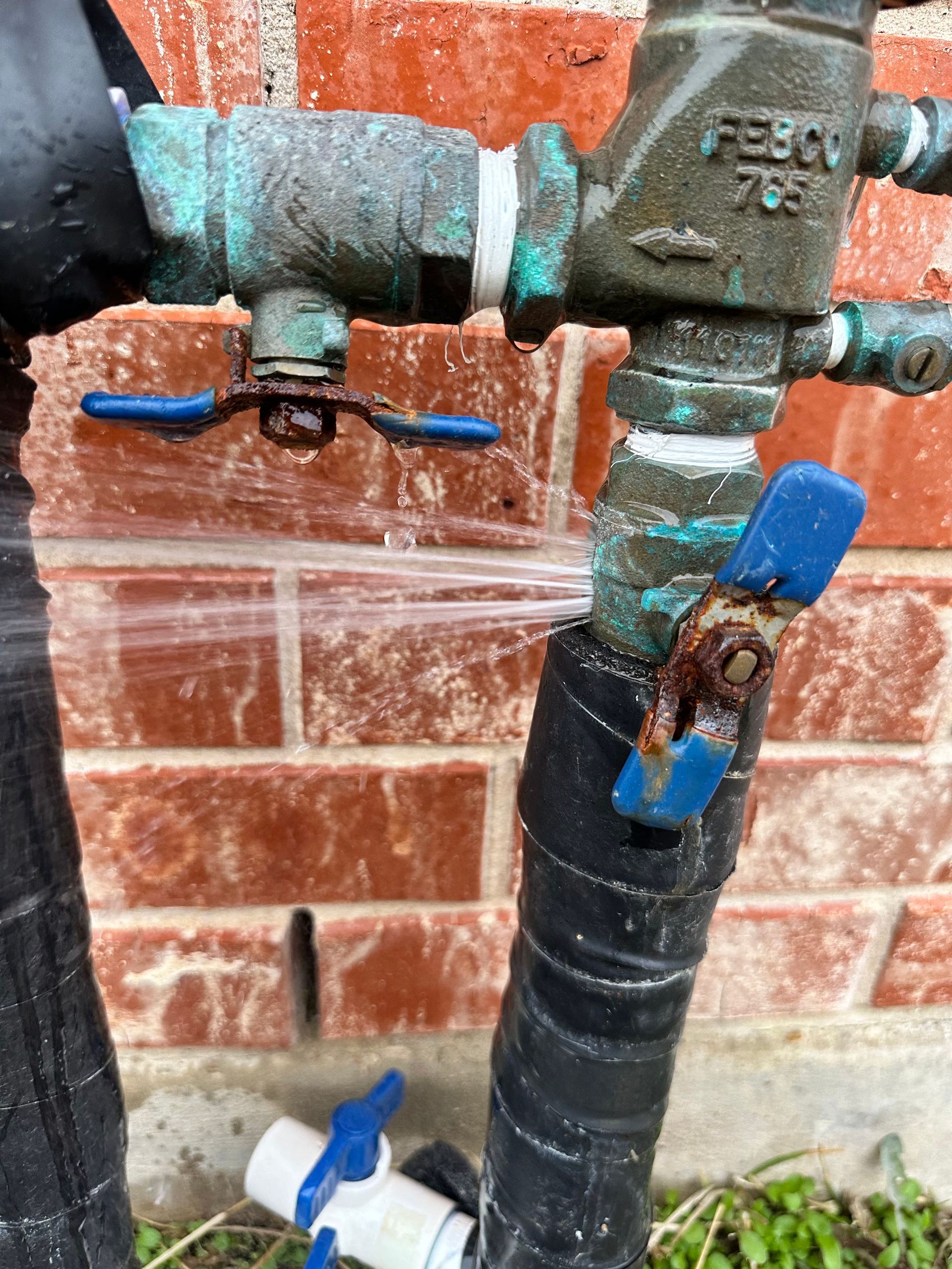 A close up of a water valve with a brick wall in the background