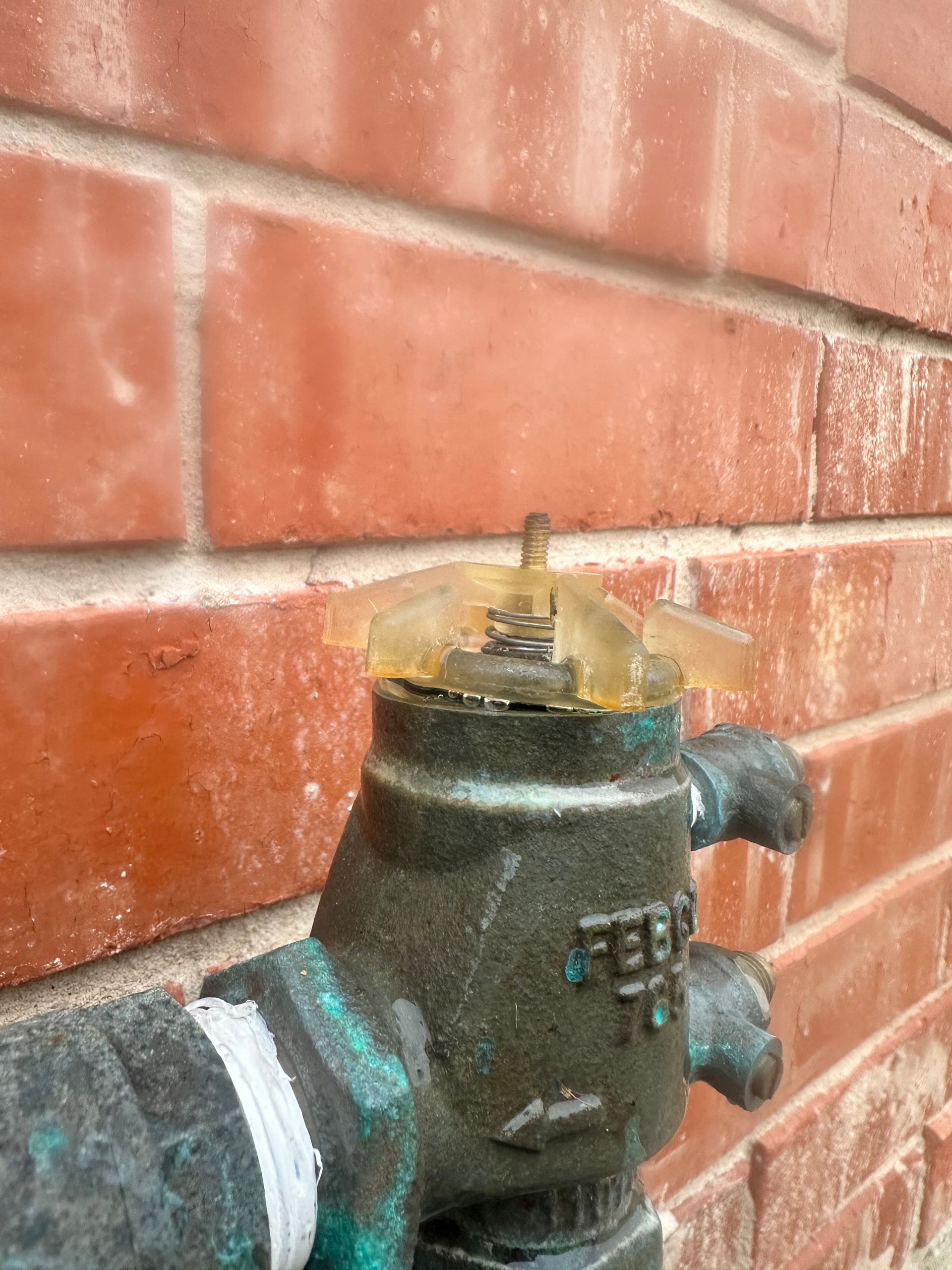 A close up of a water valve on a brick wall.