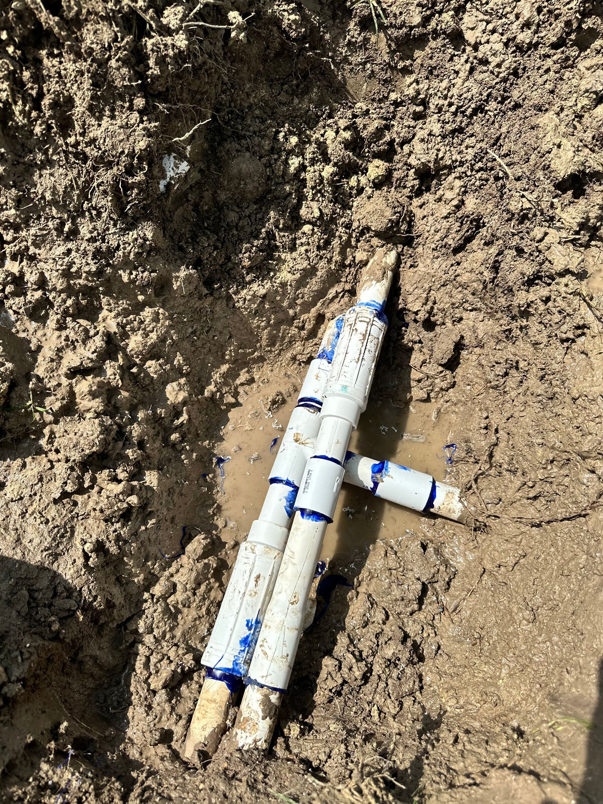A couple of pvc pipes are laying in the mud.