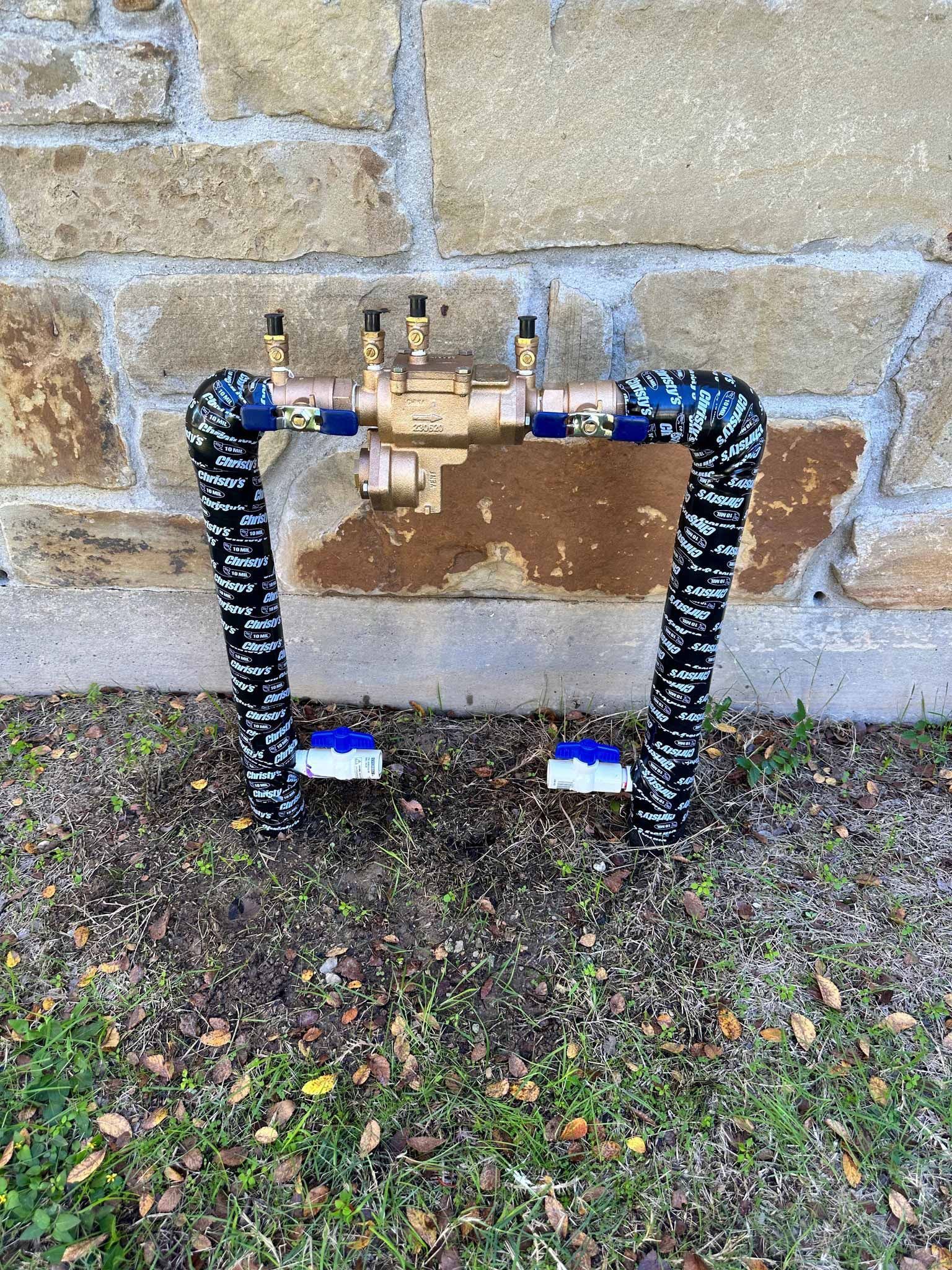 A water pipe is sitting on the ground in front of a brick wall.