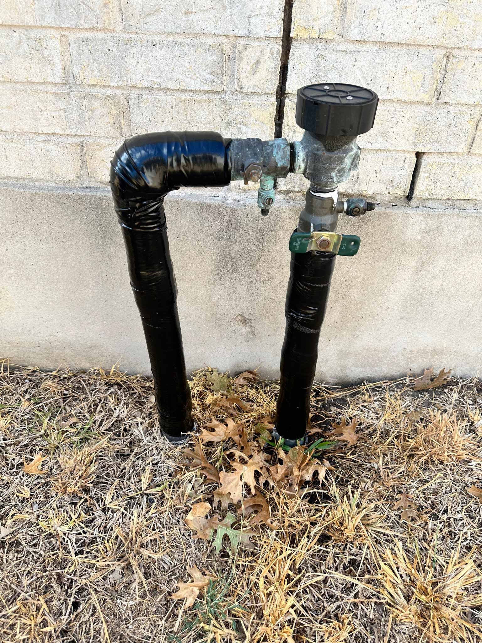 A black pipe is sitting on the ground next to a wall.