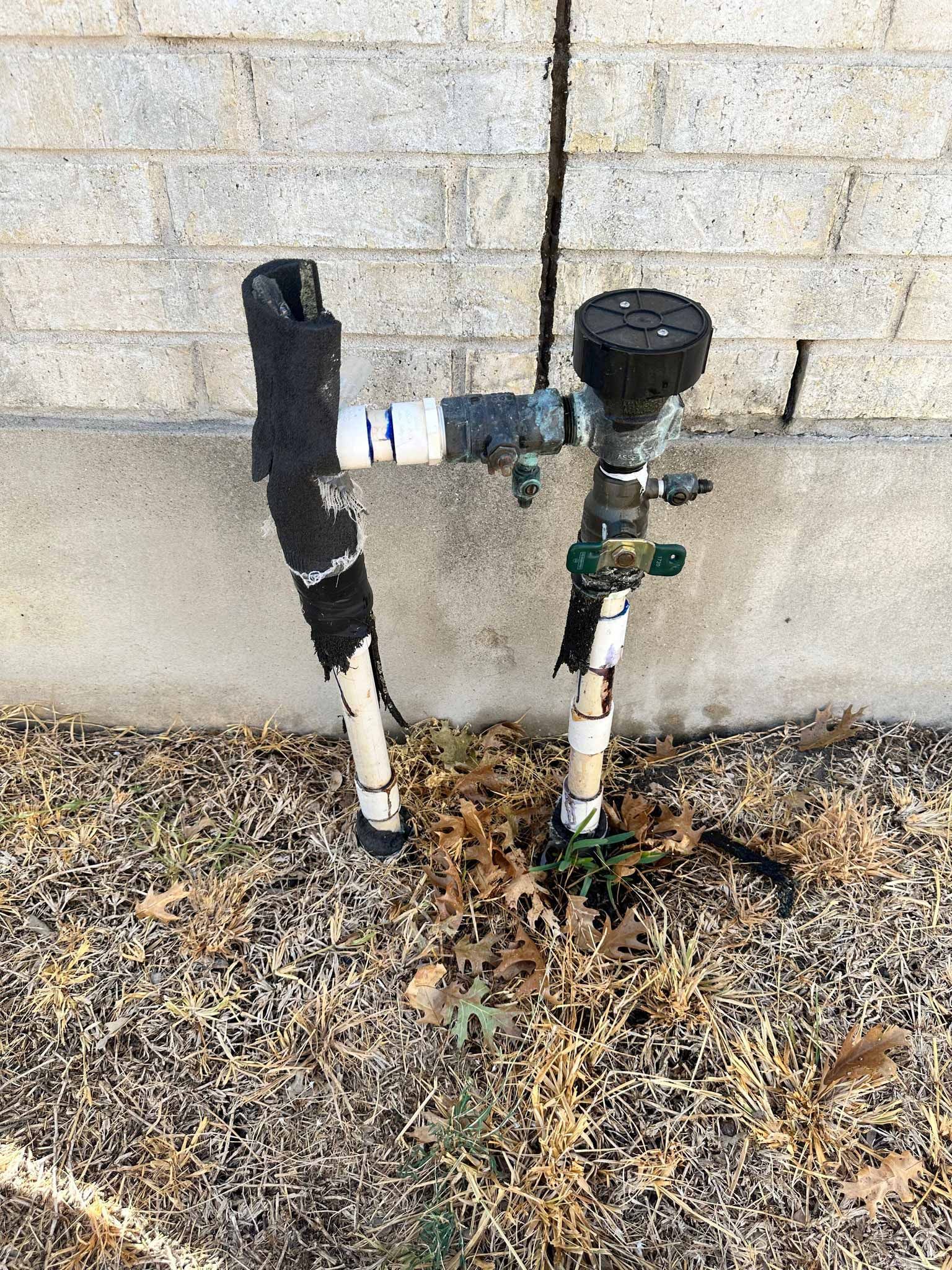 A couple of water pipes sitting next to a brick wall.