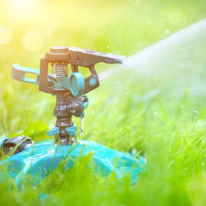 A sprinkler is spraying water on a lush green field.