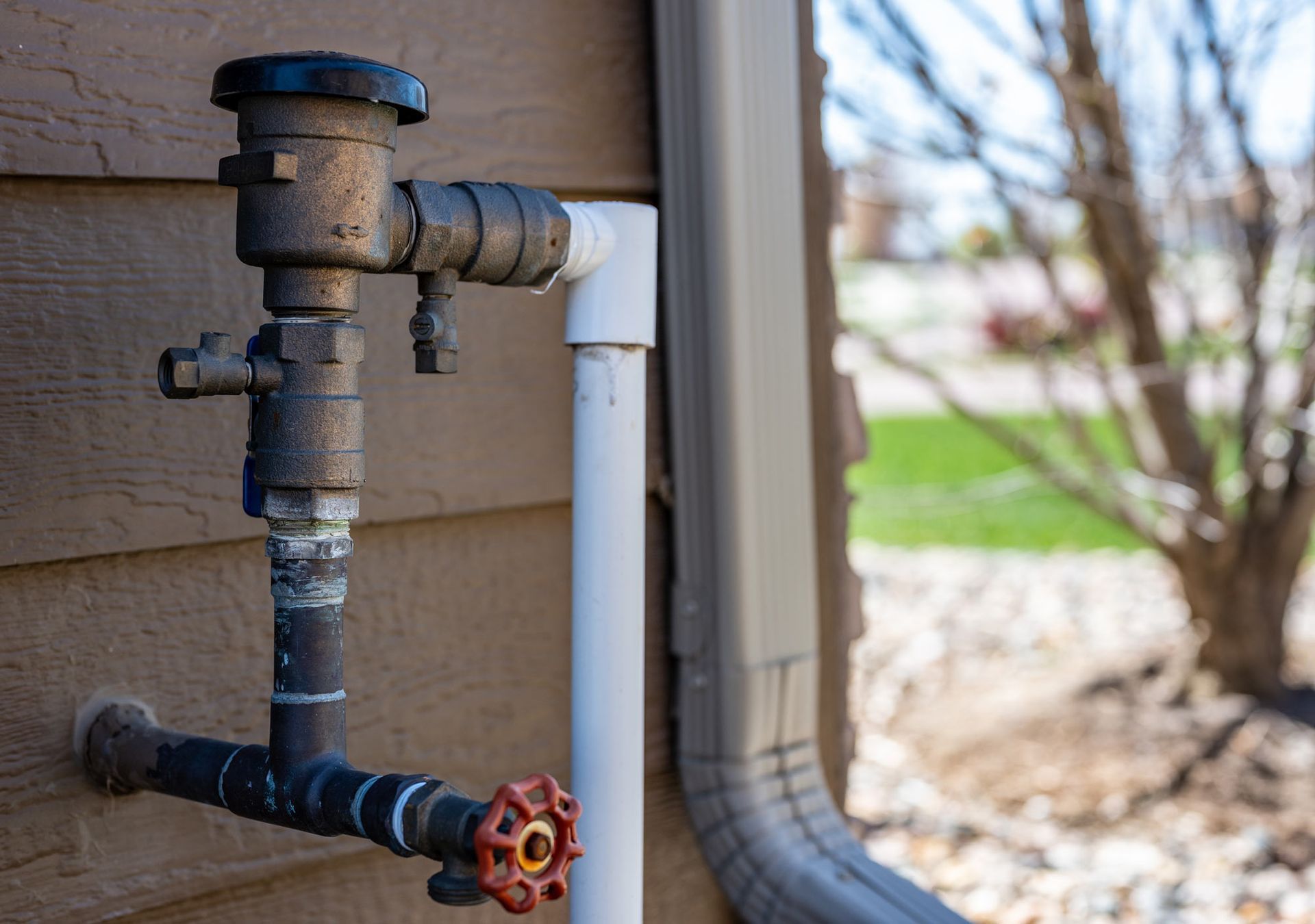 A close up of a water pipe on the side of a house.